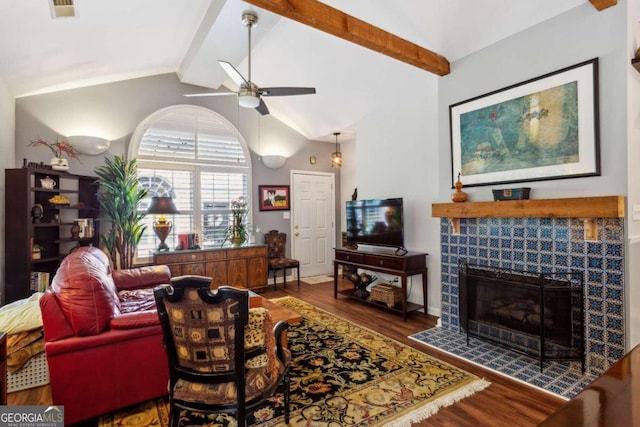 living room featuring high vaulted ceiling, ceiling fan, beam ceiling, a tiled fireplace, and hardwood / wood-style floors