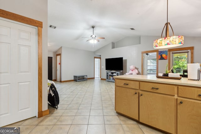 kitchen with light tile patterned floors, ceiling fan, hanging light fixtures, vaulted ceiling, and light brown cabinets