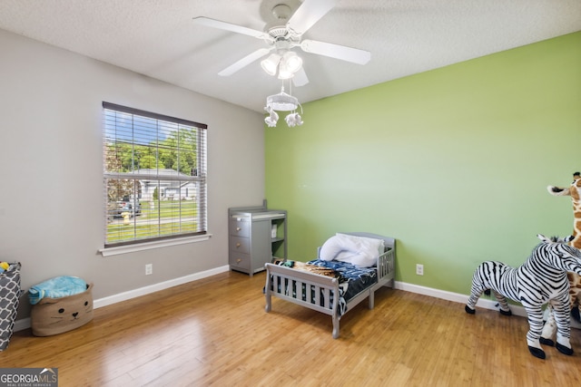 bedroom with ceiling fan, light hardwood / wood-style floors, and a textured ceiling