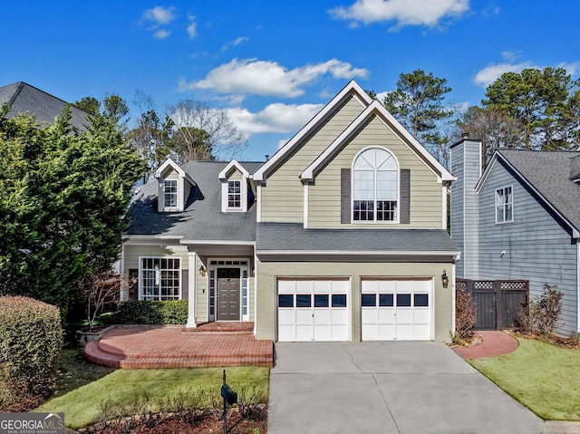 traditional home with a garage, concrete driveway, brick siding, and fence