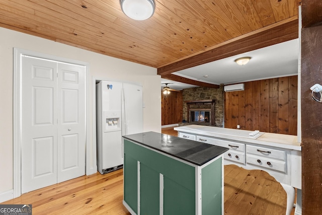 kitchen featuring a wall mounted AC, white refrigerator with ice dispenser, a center island, green cabinetry, and light hardwood / wood-style flooring