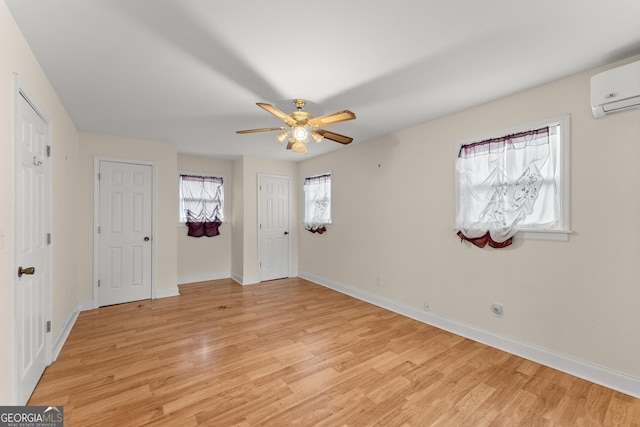 unfurnished bedroom with ceiling fan, a wall mounted air conditioner, and light hardwood / wood-style floors