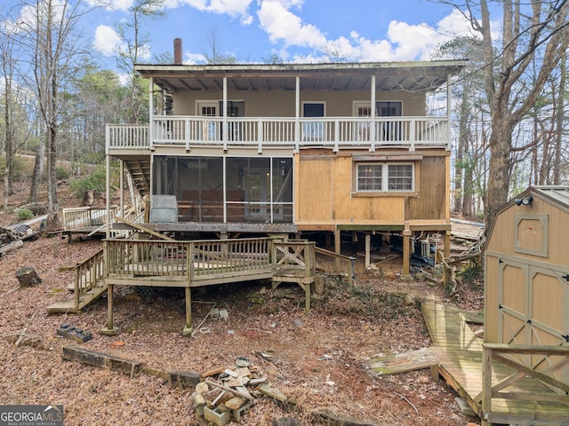 rear view of property with a shed, a wooden deck, and a sunroom