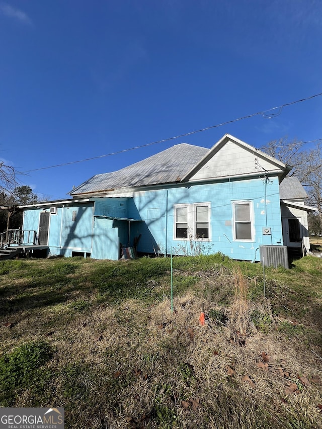 rear view of property featuring a yard and cooling unit