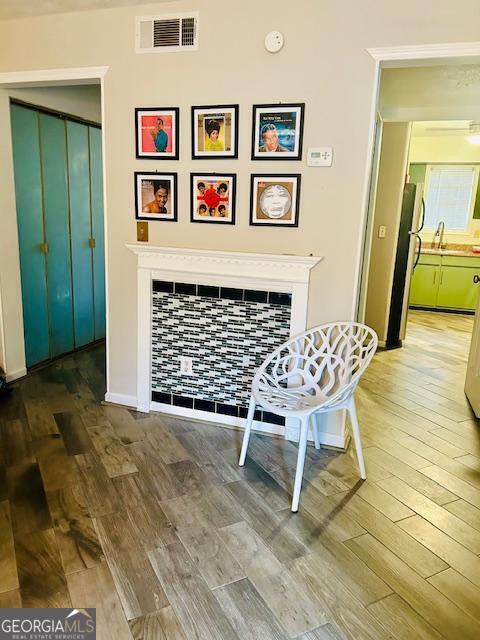 interior space with refrigerator, wood finished floors, visible vents, baseboards, and a tiled fireplace