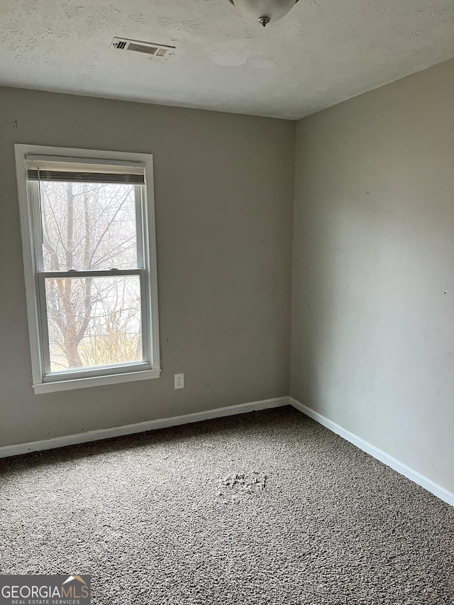 carpeted spare room featuring a textured ceiling