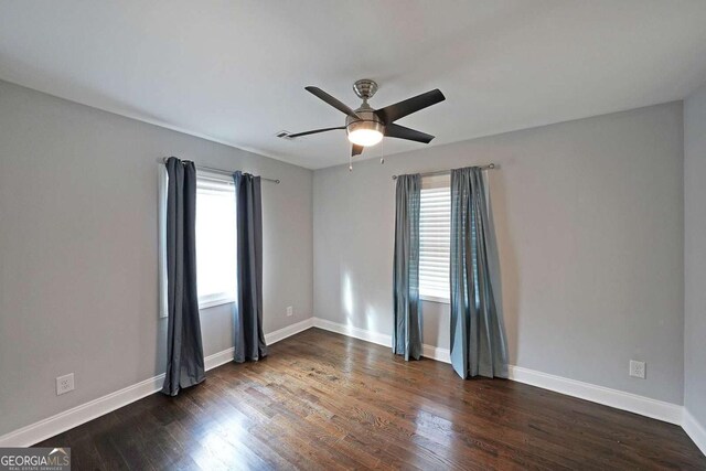unfurnished room featuring plenty of natural light, dark hardwood / wood-style floors, and ceiling fan