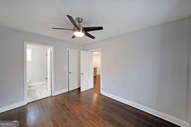 unfurnished bedroom featuring ceiling fan, ensuite bathroom, and dark hardwood / wood-style floors