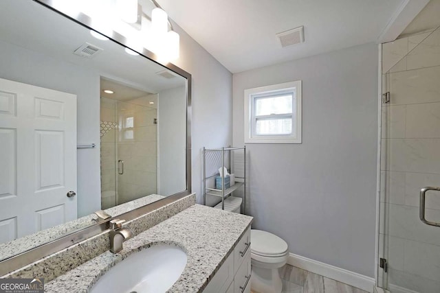 bathroom with vanity, toilet, and a shower with door