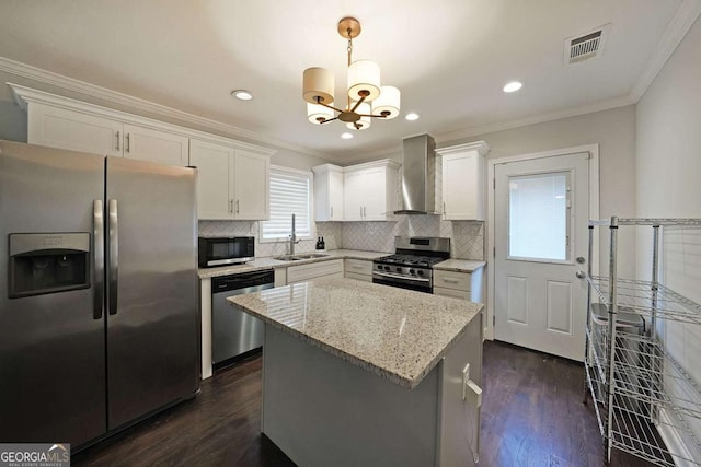 kitchen featuring pendant lighting, sink, stainless steel appliances, white cabinets, and wall chimney exhaust hood