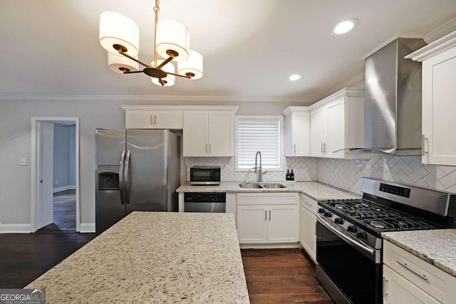 kitchen featuring appliances with stainless steel finishes, sink, hanging light fixtures, light stone countertops, and wall chimney range hood
