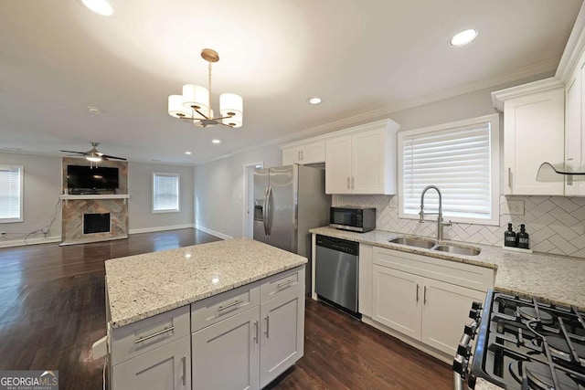 kitchen featuring pendant lighting, sink, white cabinetry, stainless steel appliances, and a large fireplace