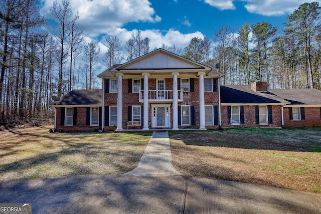 greek revival house featuring a front lawn and a balcony