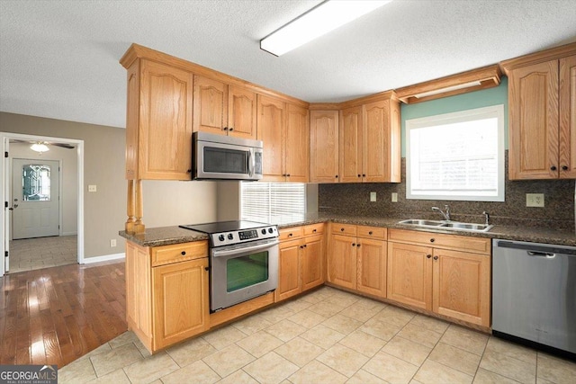 kitchen featuring stainless steel appliances, sink, dark stone countertops, and decorative backsplash