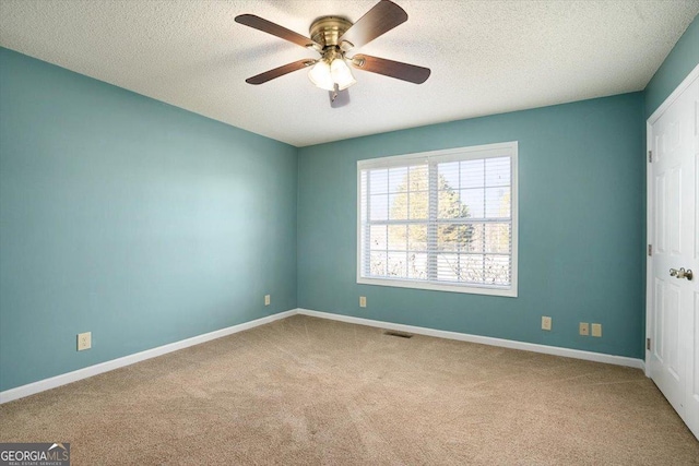 spare room with ceiling fan, light colored carpet, and a textured ceiling