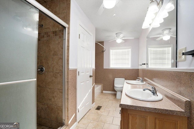 bathroom featuring vanity, ceiling fan, a shower with shower door, and toilet