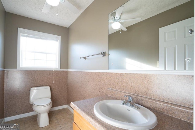 bathroom featuring vanity, ceiling fan, toilet, tile patterned floors, and a textured ceiling