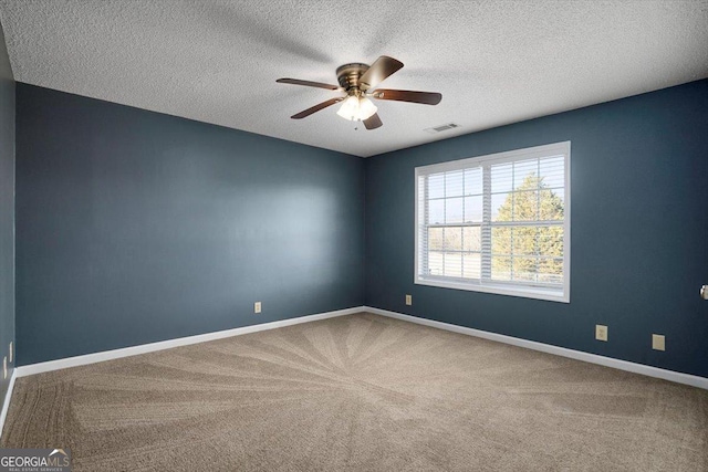 carpeted empty room featuring ceiling fan and a textured ceiling