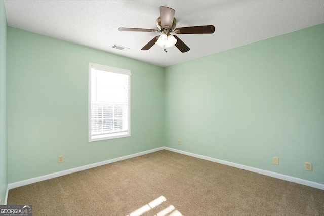 spare room featuring ceiling fan, carpet floors, and a textured ceiling