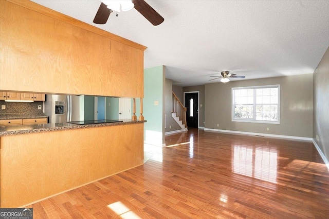 kitchen with stainless steel refrigerator with ice dispenser, light brown cabinetry, tasteful backsplash, black electric stovetop, and hardwood / wood-style floors