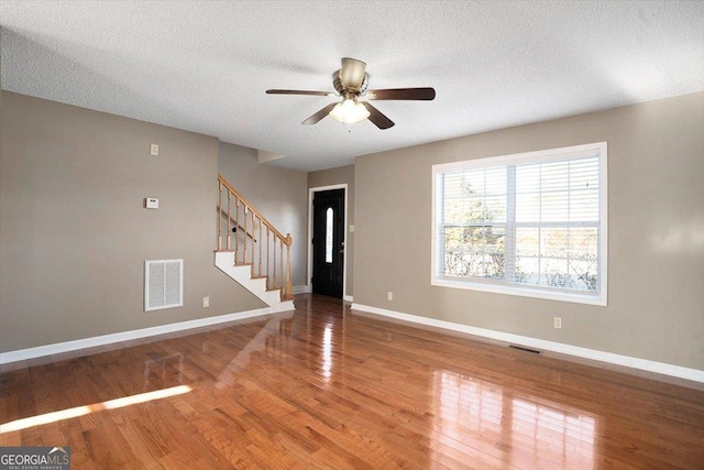 empty room with ceiling fan, wood-type flooring, and a textured ceiling