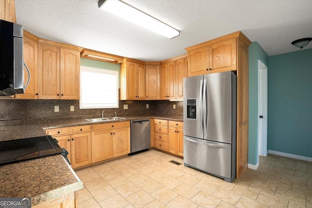 kitchen featuring sink, decorative backsplash, a textured ceiling, and appliances with stainless steel finishes