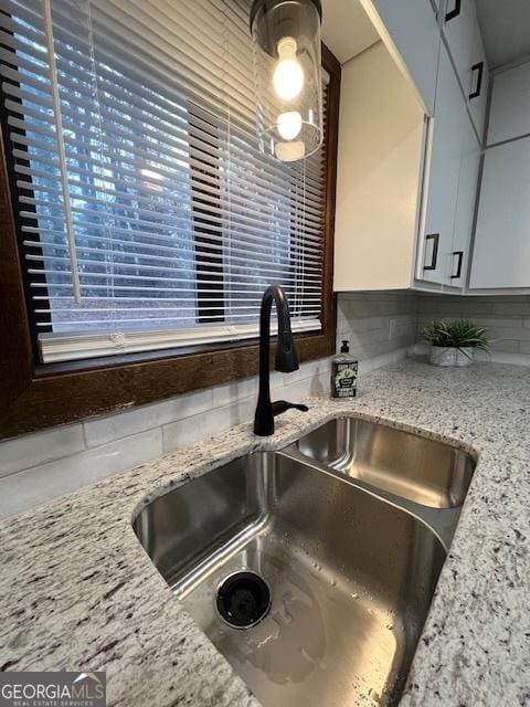 kitchen featuring light stone counters, sink, and backsplash