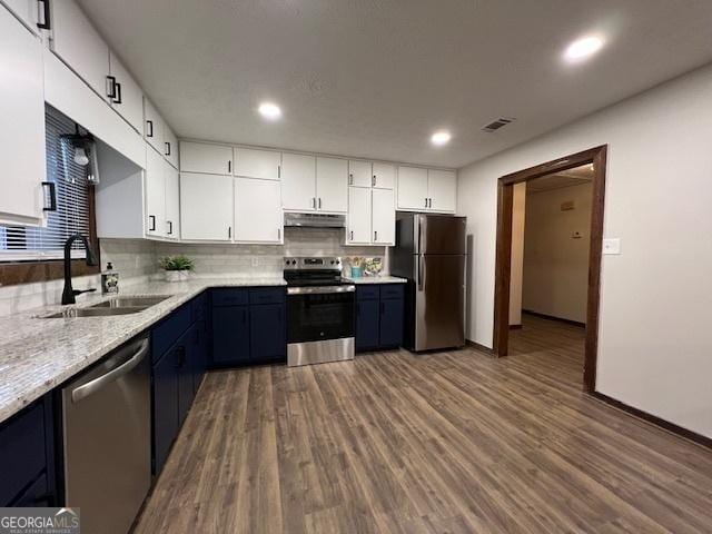 kitchen with sink, blue cabinetry, stainless steel appliances, white cabinets, and decorative backsplash