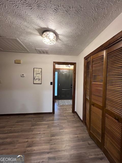 hallway with dark wood-type flooring and a textured ceiling