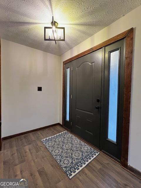 foyer entrance featuring an inviting chandelier, wood-type flooring, and a textured ceiling