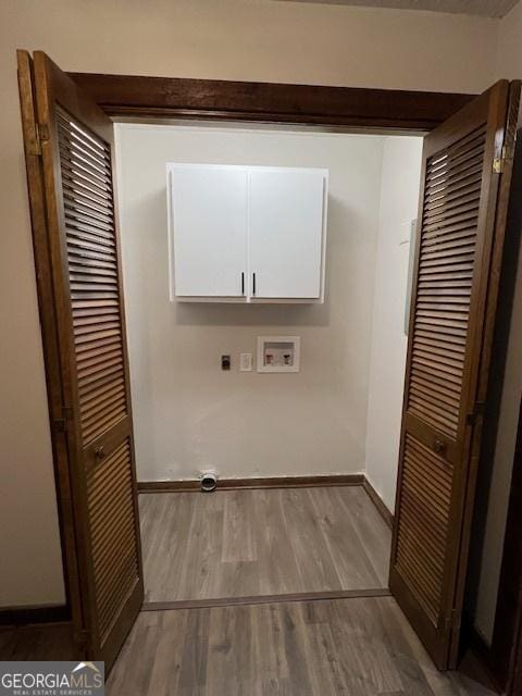 washroom featuring hookup for a washing machine, light hardwood / wood-style floors, and cabinets