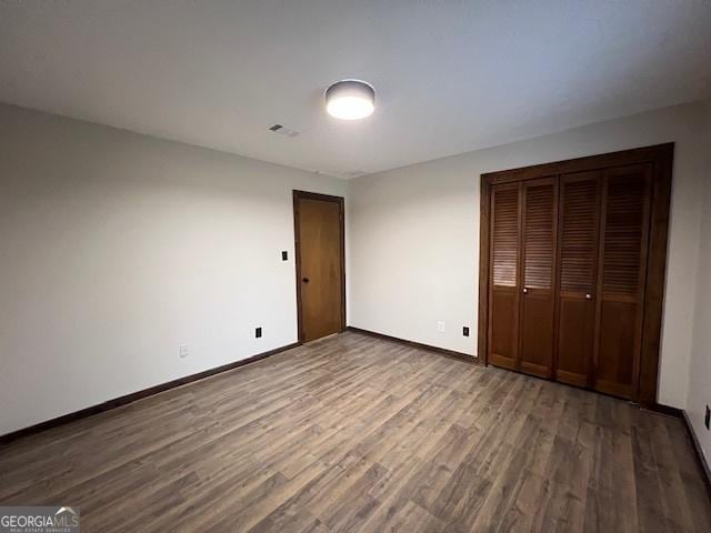 unfurnished bedroom with dark hardwood / wood-style floors and a closet