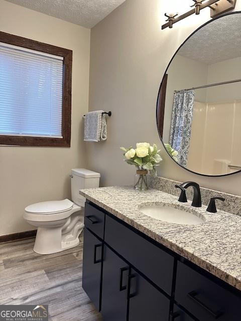 bathroom with hardwood / wood-style floors, vanity, toilet, a textured ceiling, and a shower with shower curtain