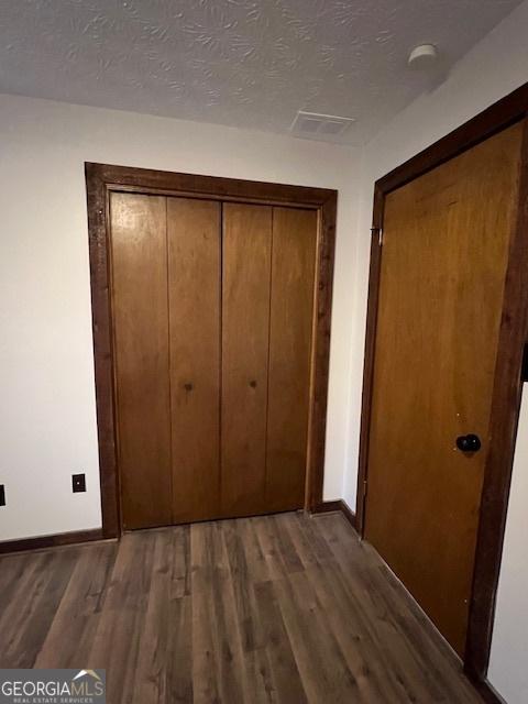 corridor with dark wood-type flooring and a textured ceiling