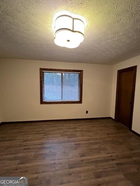 empty room featuring dark hardwood / wood-style floors and a textured ceiling