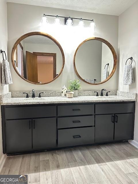 bathroom featuring hardwood / wood-style flooring, vanity, and a textured ceiling