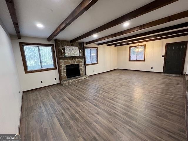 unfurnished living room featuring beam ceiling, plenty of natural light, dark wood-type flooring, and a fireplace