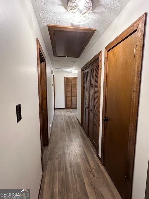 hallway featuring wood-type flooring and a textured ceiling