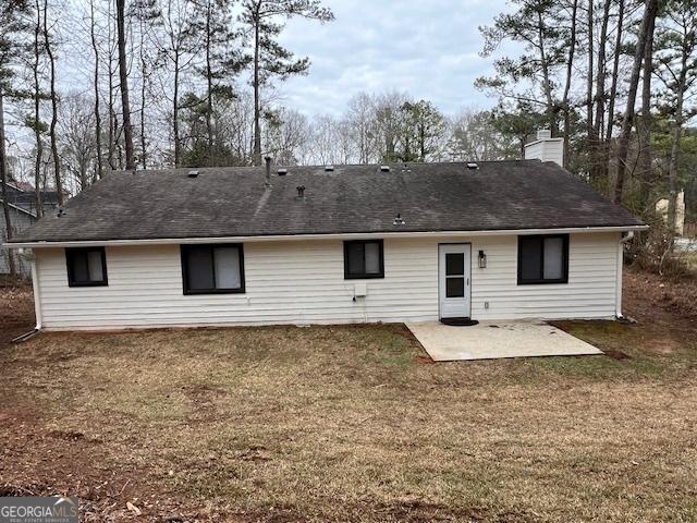 rear view of house with a patio and a lawn