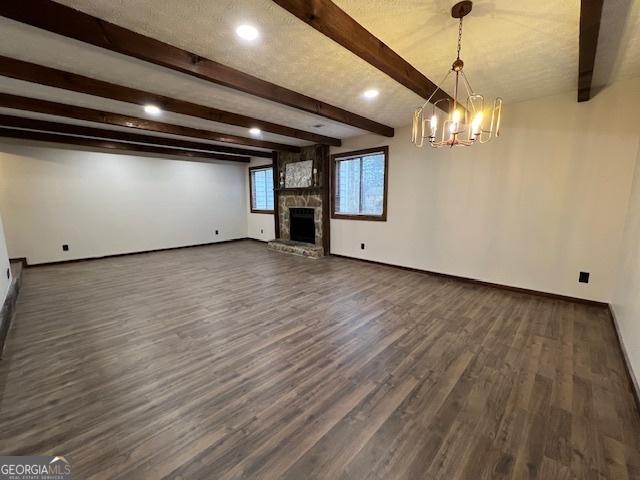 unfurnished living room featuring a fireplace, dark hardwood / wood-style floors, beam ceiling, and a notable chandelier