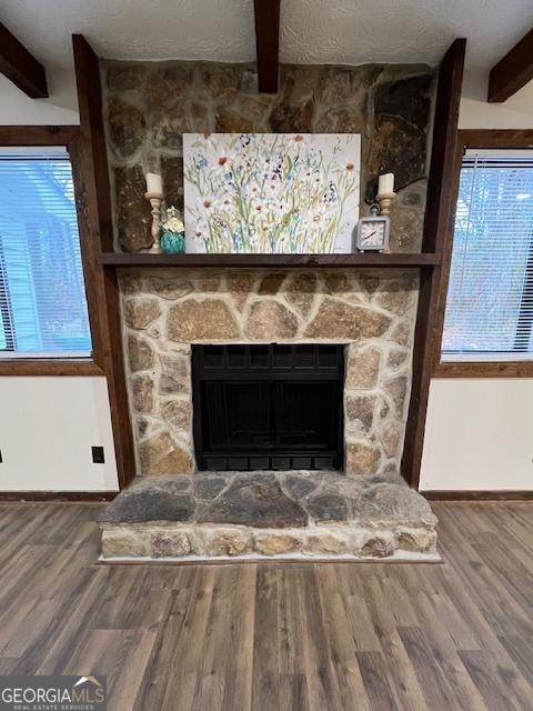 interior details with beam ceiling, wood-type flooring, a textured ceiling, and a fireplace