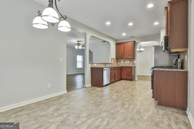 kitchen featuring arched walkways, decorative light fixtures, appliances with stainless steel finishes, a ceiling fan, and light stone countertops