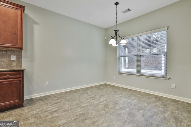 unfurnished dining area featuring a chandelier, visible vents, baseboards, and wood finished floors