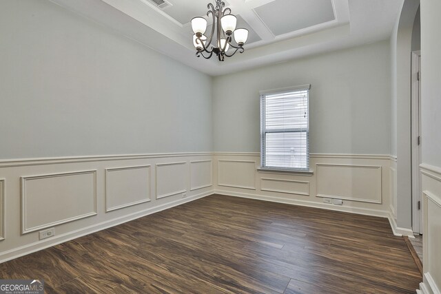 spare room featuring an inviting chandelier, visible vents, coffered ceiling, and dark wood-style flooring