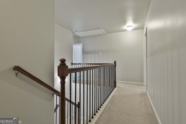 hall with baseboards, an upstairs landing, and light colored carpet