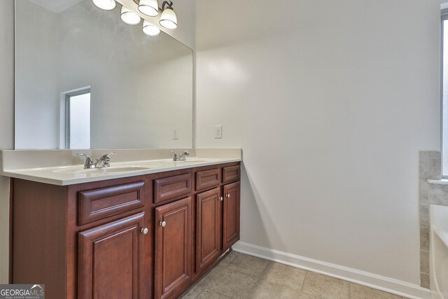 full bathroom featuring a sink, baseboards, and double vanity