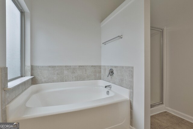 bathroom featuring a shower stall, a bath, and tile patterned floors