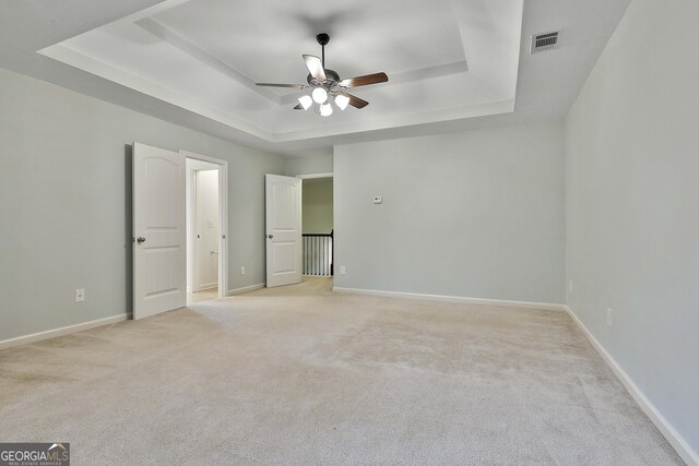 unfurnished bedroom with light carpet, a raised ceiling, visible vents, and baseboards