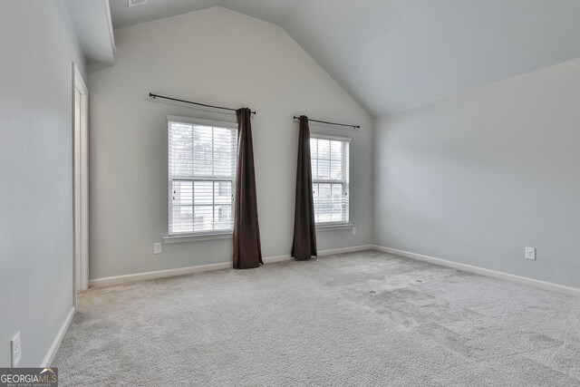 unfurnished room with high vaulted ceiling, light carpet, and baseboards