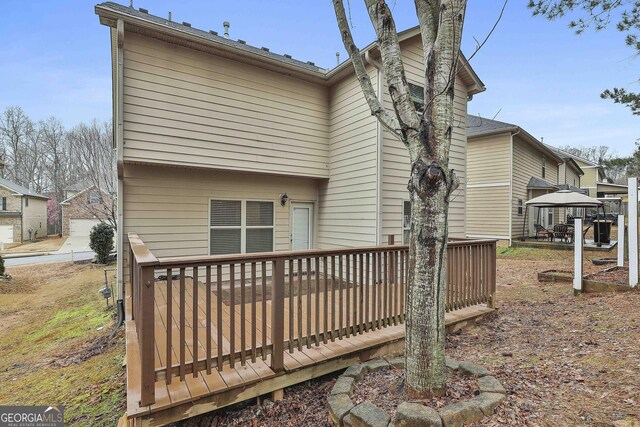 rear view of property with a deck and a gazebo